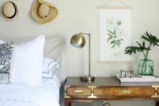 a boho bedroom with grey walls, a grey bed with printed bedding, a stained desk, a basket and a hat gallery wall