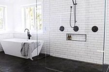 a bold and contrasting modern bathroom with a floor transition from black hex tiles to laminate, a shower space and a bathtub