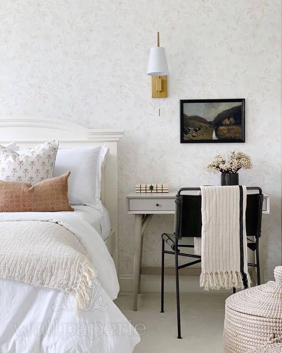 a cozy neutral bedroom with a cottage feel, a bed with neutral bedding, a grey desk, a black chair and a basket with a lid