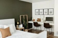 a lovely and functional bedroom with an olive green accent wall, a white bed with bedding, built-in desk, black chairs and a gallery wall