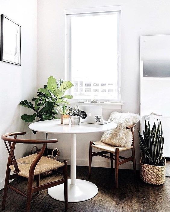 a lovely modern breakfast corner with a couple of comfy chairs, a round table and some plants invites in