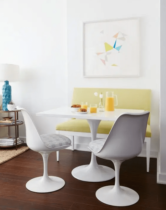 a modern and bright breakfast nook with a mustard loveseat, a white table and catchy white chairs with upholstery