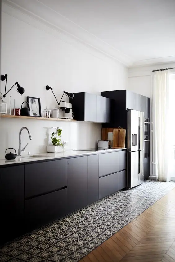 a modern black kitchen with sleek cabinetry, a white backsplash and countertop, a printed tile floor to parquet and black sconces