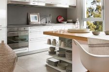 a modern white kitchen with a concrete backsplash, a grey tile floor transitioning into laminate, a kitchen island and chairs