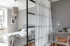 a pretty Scandinavian bedroom in shades of grey, with a glass space divider for a home office nook is a functional idea