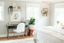 a pretty boho bedroom with a navy desk and a faux fur chair, a floating shelf and potted plants, neutral bedding and a printed rug