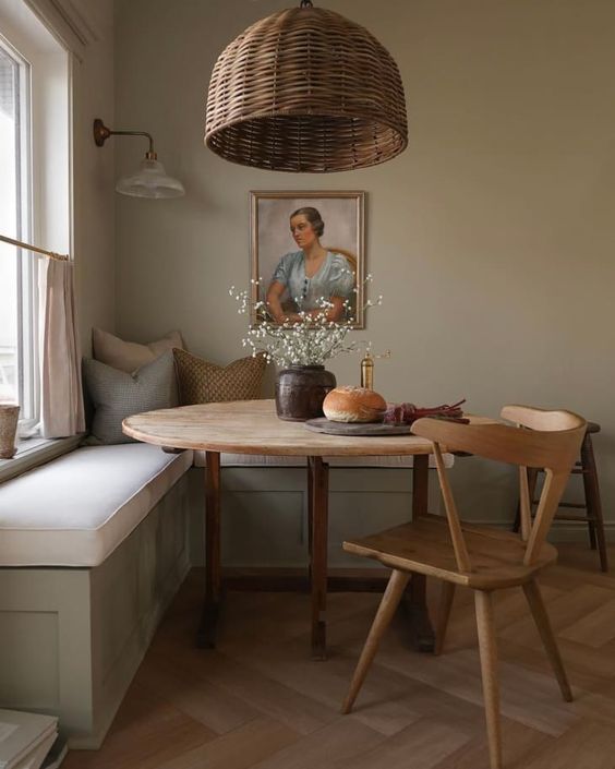 a refined modern farmhouse breakfast corner with a built-in seat, a round table and a stained chair, a woven pendant lamp and an artwork