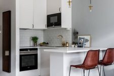 a small Scandinavian kitchen with sleek white cabinets, a kitchen island, a grey tile floor that transitions into a white tile one