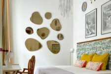 a whimsical bedroom with a bed with a printed headboard, colorful and printed bedding, some art, a gallery wall of mirrors, a desk and a chair