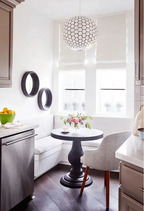 a white corner banquette seating and a small black round table for a tiny breakfast nook by the window