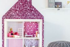 an IKEA Expedit piece turned into a doll house, with fuchsia printed wallpaper, some dolls and toys