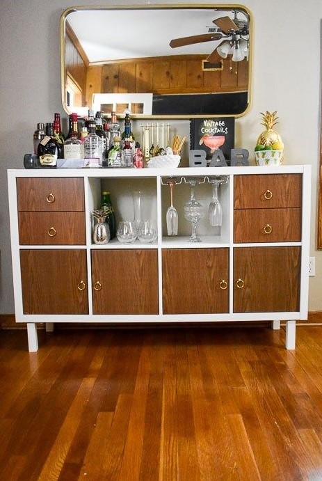 an IKEA Kallax unit hack into a mid-century modern bar with drawers and doors of stained wood