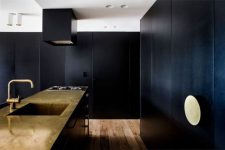 black kitchen clad with textured panels and a copper kitchen island