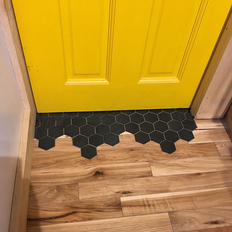 a slight curb to transition out of the bathroom might work really well (via @garnerwoodworking)