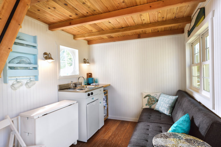 this beach cottage features different space saving solutions like a mini fridge, a sectional sofa and an IKEA's folding dining table that can seat 4 comfortable (Tiny Digs)