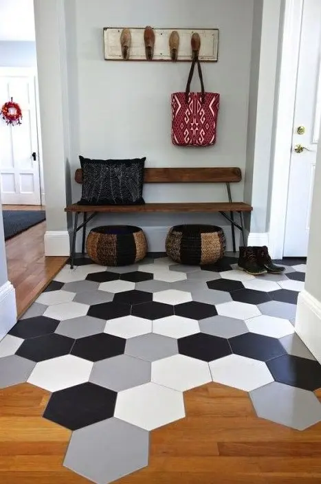 Large scale hexagon tiles in different colors in the entryway flow into warm colored laminate in the rest of the space