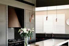 moody kitchen with dark panelled cabinetry and leather pulls