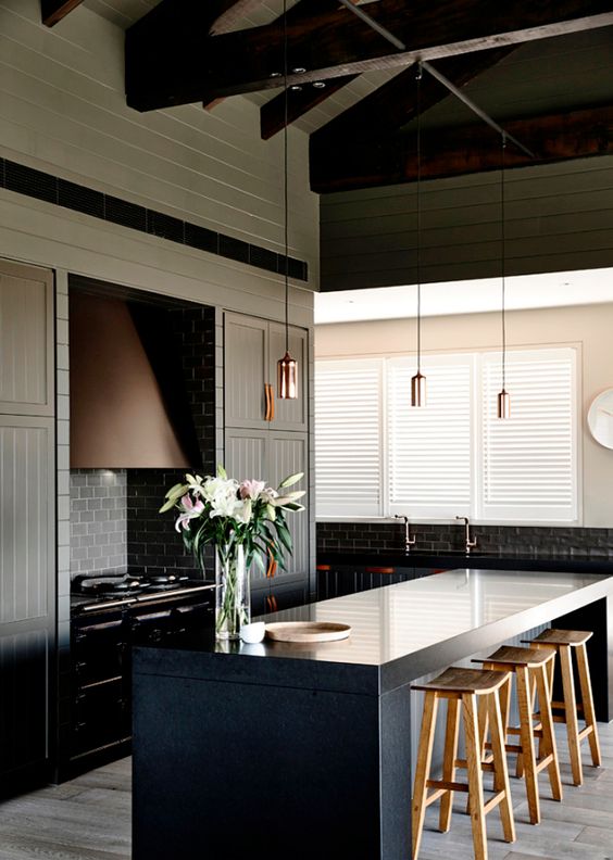 moody kitchen with dark panelled cabinetry and leather pulls
