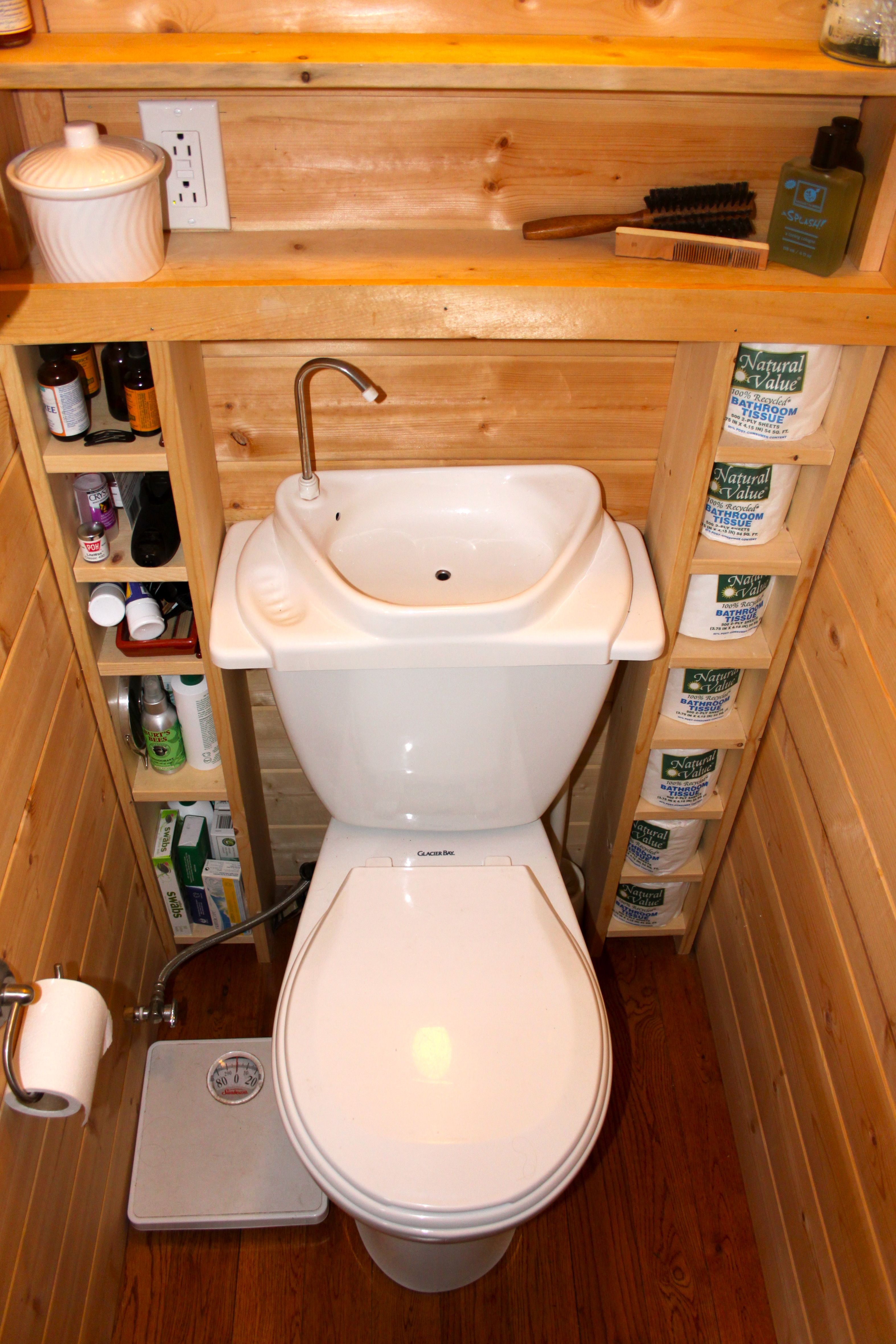 a tiny cottage bathroom that features a porcelain toilet/sink combo and an open shelving unit