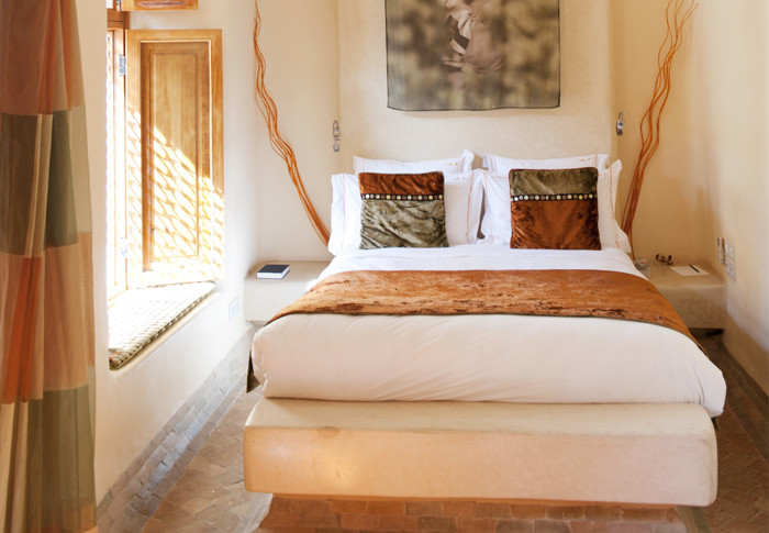 This Africa inspired bedroom has light walls and various shades of ocher used for decor and textiles