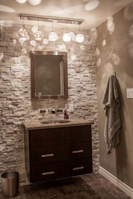 grey powder room with a stone accent wall and a modern dark wood vanity