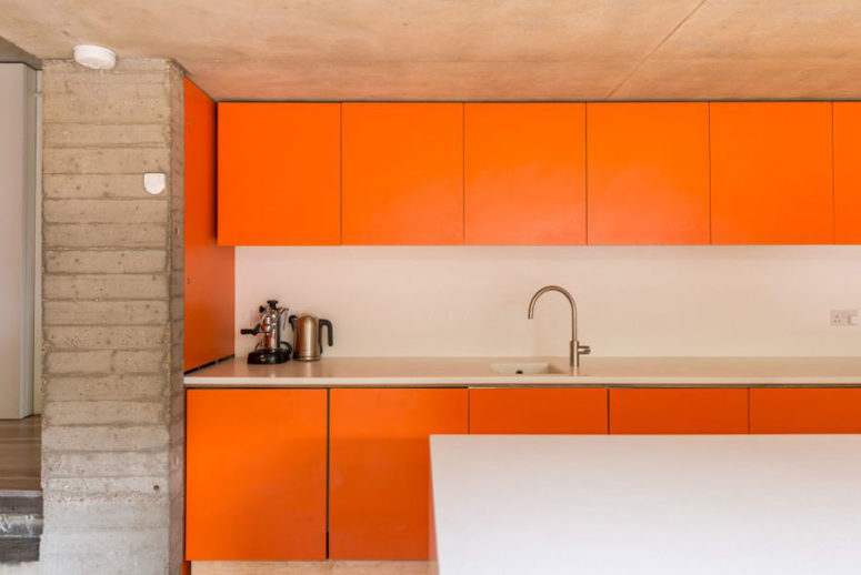 Concrete kitchen walls are a nice juxtaposition for bold orange color