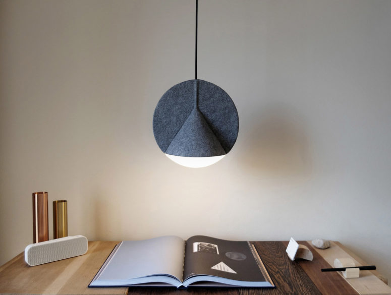 The lamp reminds of a flat disc bisecting a wide, three-dimensional cone