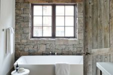03 faux stone wall and weathered wood on the floor make this bathroom cabin-like