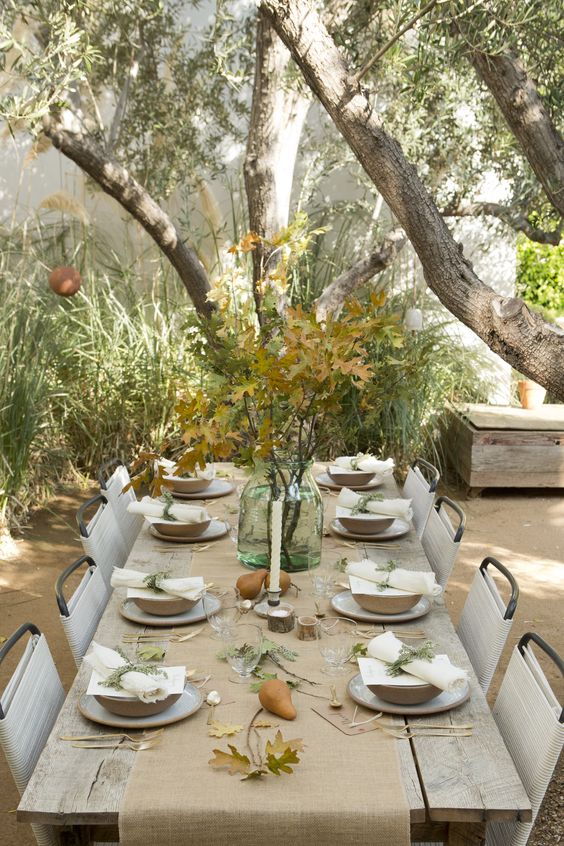 neutral table with a burlap table runner, fall leaves in a jar, pears and greenery