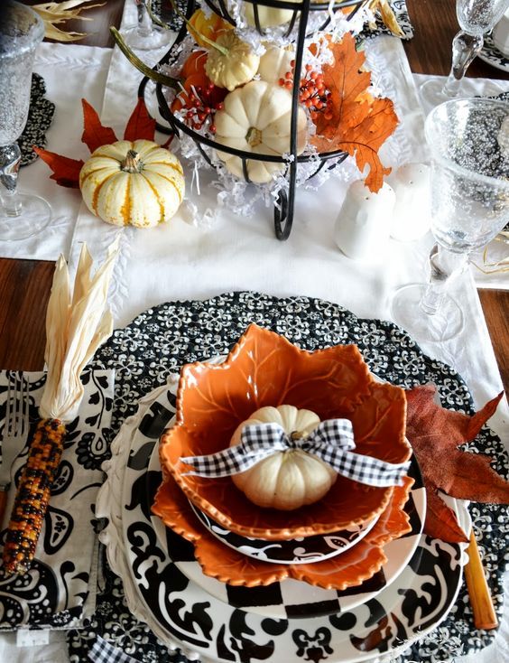 patterned black and white chargers, pumpkins with a black and white bow, pumpkins in a wire stand