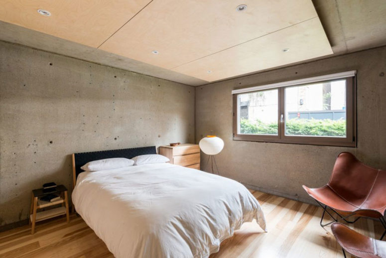 The guest bedroom is decorated with concrete and warm-colored wood, it's very laconic