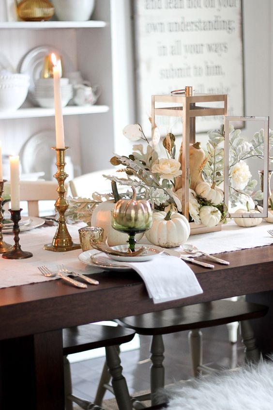 white and ivory table setting with gilded candle holders and silver pumpkins