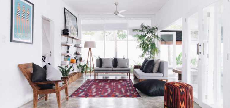The lounge space is decorated with a bold rug and lots of island potted greenery