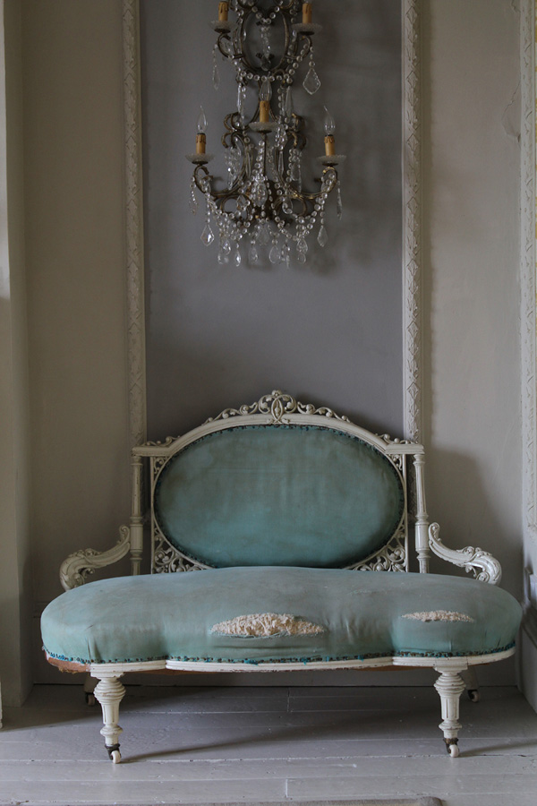 This green love seat is shabby chic, and it looks amazing with a vintage chandelier