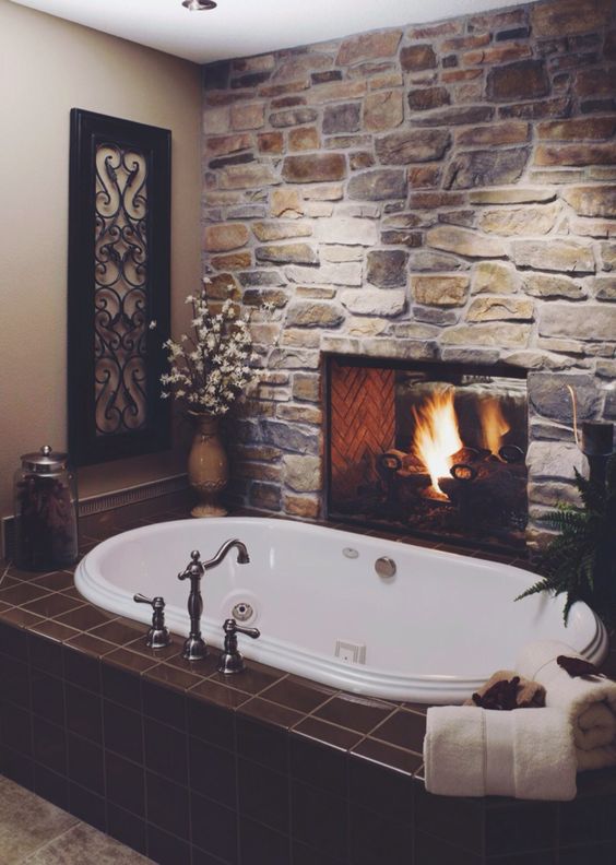 rough stone wall with a fireplace makes a bathroom inviting