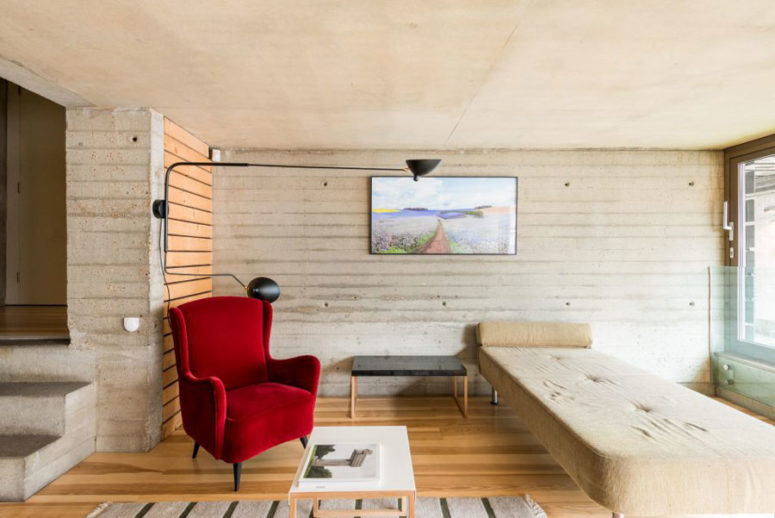 Concrete walls and wooden floor look contrasting with bold red chairs