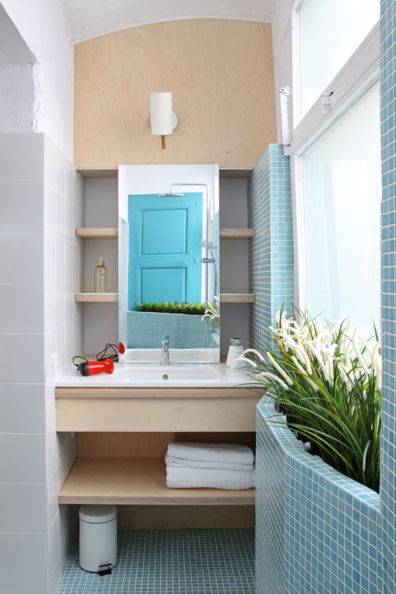 The bathroom is fully clad with small blue tiles and there's a lot of greenery
