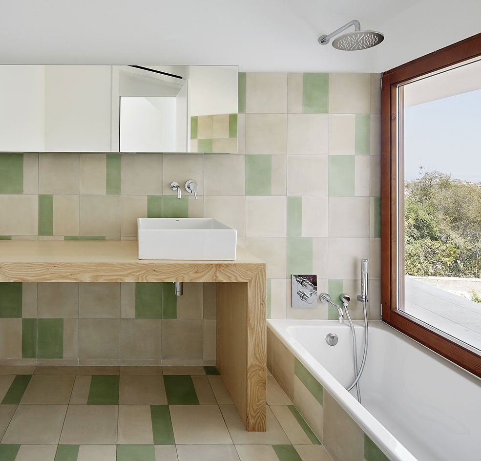 The combination of modern sustainable features and traditional materials create a welcome balance, while the green tiles link the minimalist space visually to the green nature outside