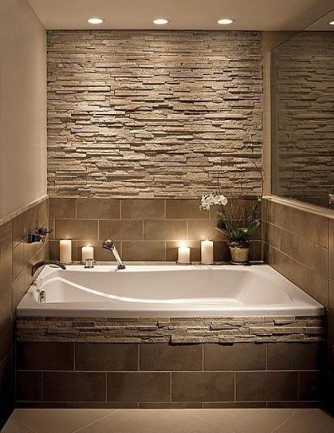 stone accent wall and bathtub decor in earthy colors