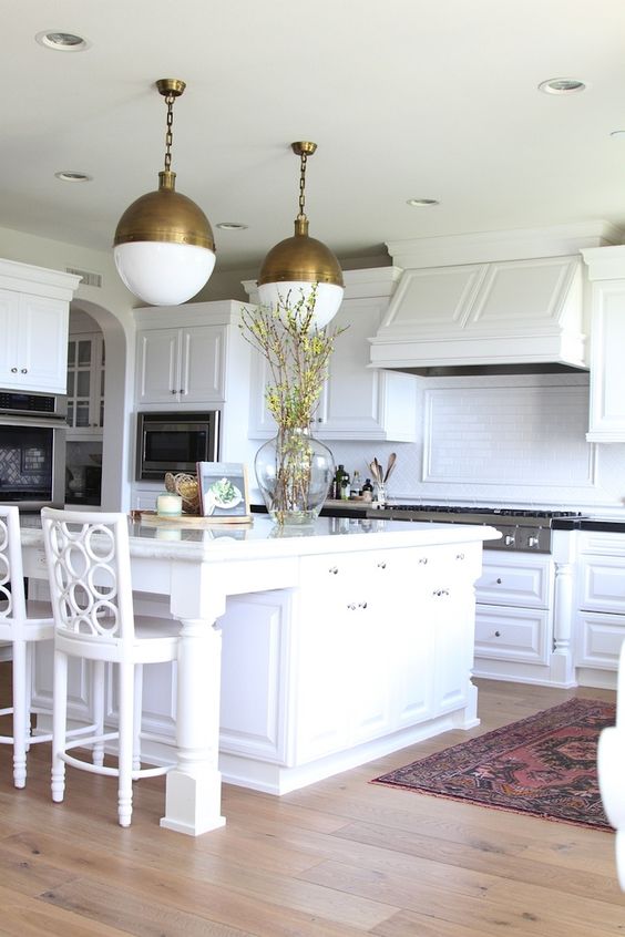 warm wood floors for an all-white kitchen and ceramic tile backsplash