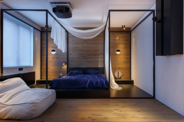 12 The bedroom features a wooden wall behind the bed and two metal structures that are almost like opposite canopies