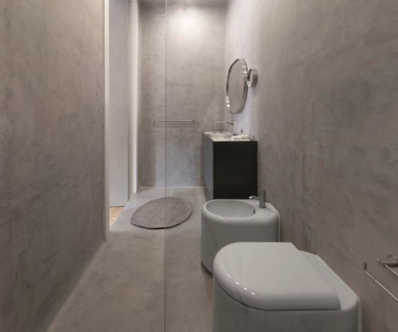 The bathroom is small, clad with marble-inspired tiles
