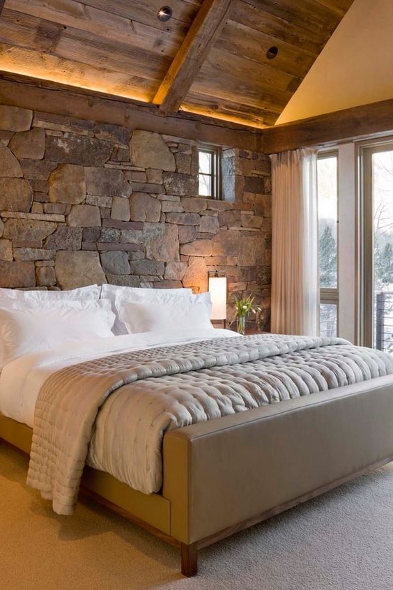 natural stone accent wall behind the headboard makes this bedroom cozier and more inviting