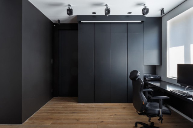 The home office is clad with dark panels, which hide everything until the owner needs it