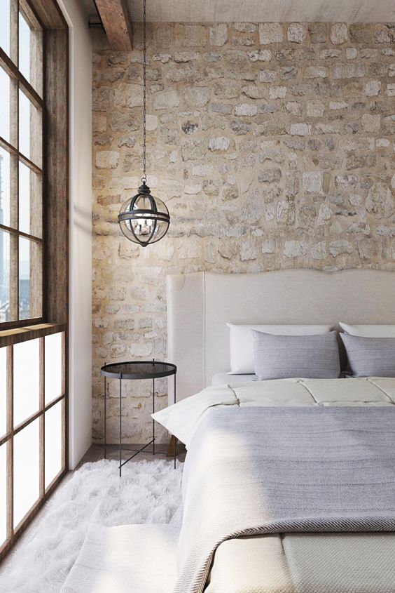 airy chic bedroom with stone clad that looks antique and adds a refined touch