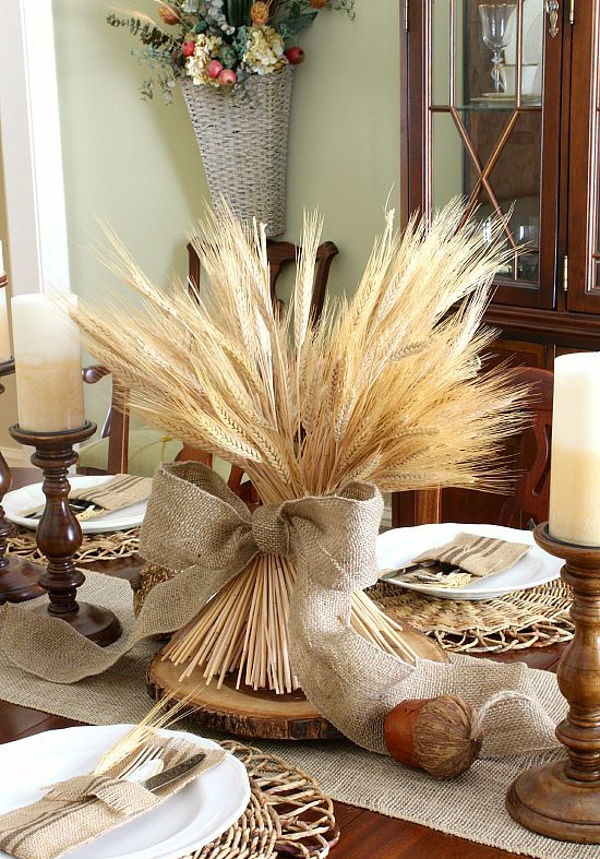 wheat centerpiece with a burlap bow, woven chargers, candles in wooden candle holders
