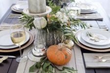 19 natural pumpkins, greenery and large candles on a fabric table runner
