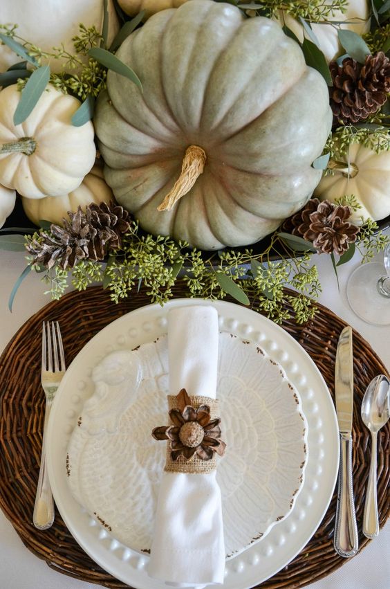 fall pumpkins, pinecones and greenery centerpiece, a woven charger and a pinecone napkin ring