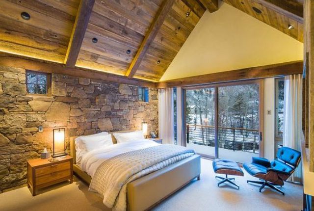 natural stone headboard wall and a wooden ceiling