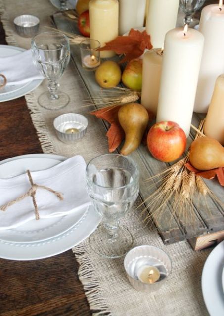board with apples, pears and candles on a fabric table runner